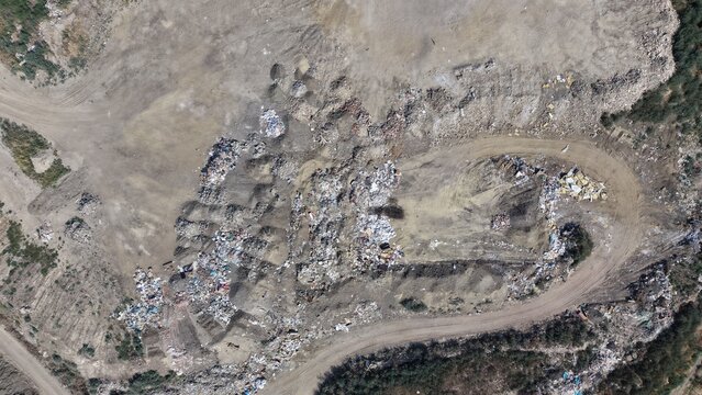 Aerial view of a large landfill site with piles of waste, dirt access roads, and industrial debris in Pancevo, Serbia.