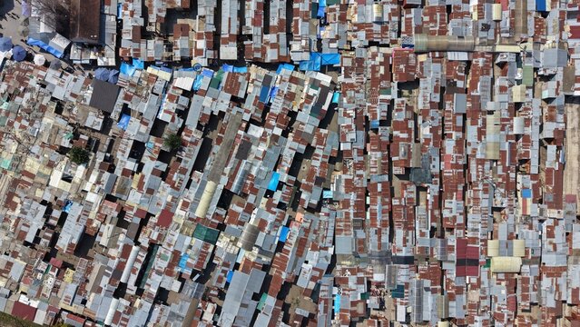 Aerial view of a dense market area featuring rows of stalls with weathered corrugated metal roofs and narrow pathways in Pancevo, Serbia.