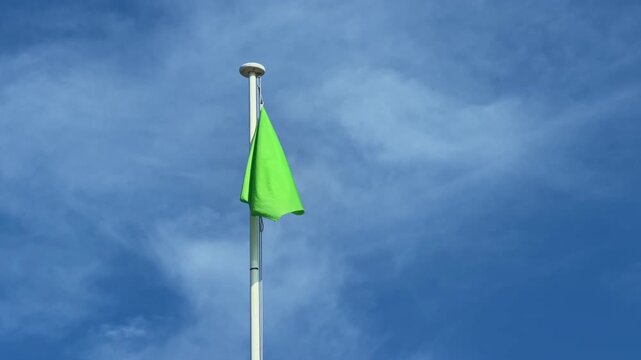 Closer view of a green safety flag indicating safe swimming conditions at the Mediterranean beach environment.