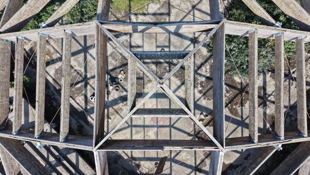 Aerial view of a wooden roof structure with geometric beams casting shadows on the ground below in Pancevo, Serbia.