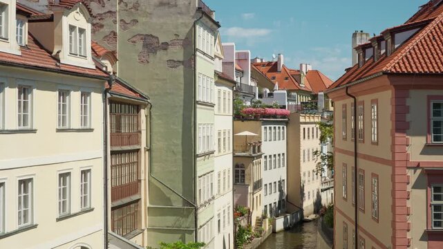 Historic residential buildings line the narrow Certovka canal in Prague. Scenic waterway flows between colorful old houses in Mala Strana district. It is an iconic European travel destination.