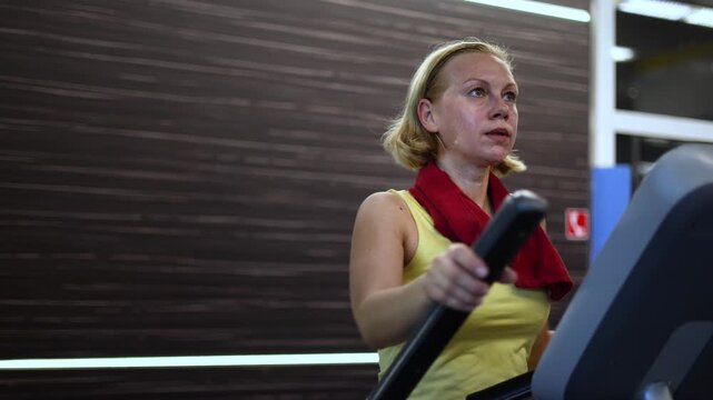 Watch this inspiring close-up of a middle-aged woman engaged in a cardio workout on a step machine, showcasing her dedication to fitness and the importance of maintaining a healthy lifestyle.
