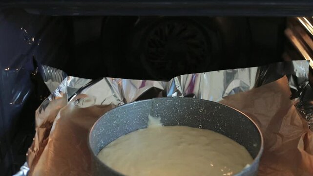 A woman's hand places a pan filled with pie batter into a preheated oven, ready to bake a homemade pie surrounded by foil-lined shelves