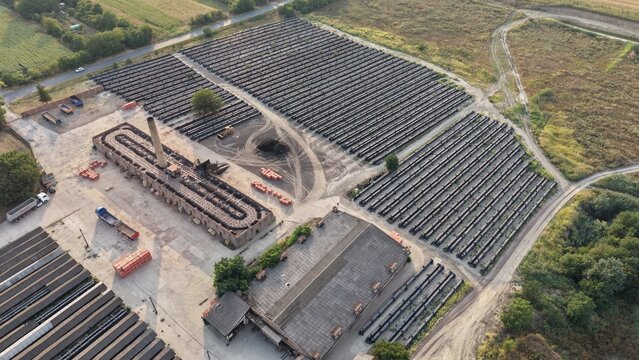 Aerial view of the historic Ciglana brickworks featuring rows of stacked bricks, a tall chimney, and industrial buildings surrounded by rural landscape in Pancevo, Serbia.
