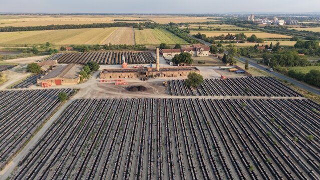 Aerial view of the historic Ciglana brickworks in Pancevo, featuring long rows of drying bricks, a tall chimney, and surrounding agricultural fields in Pancevo, Serbia.