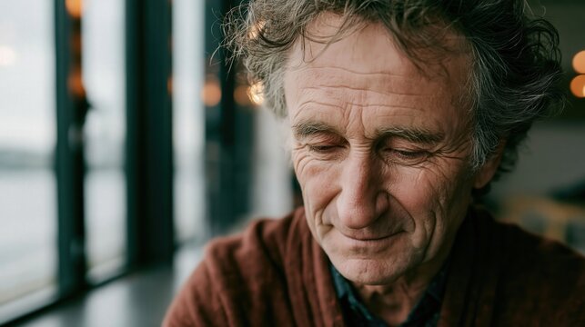 Thoughtful older man with curly hair gazes downward indoors.