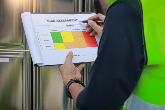Focused safety inspector holding clipboard carefully analyzes industrial risk assessment matrix document during serious site investigation