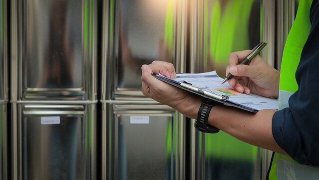 Serious inspector holds clipboard during safety chemical risk assessment audit showing professional diligence at industrial storage site