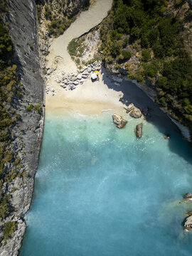Aerial view of the turquoise waters of Xigia Beach, surrounded by steep limestone cliffs and lush greenery in Zakinthos, Greece.