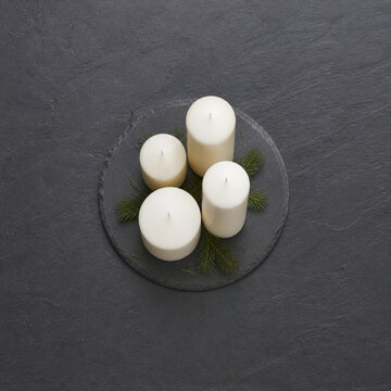 Overhead square view of four unlit ivory pillar candles of different