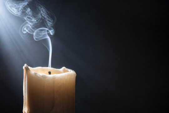 A candle that has just been extinguished with a thin ribbon of smoke