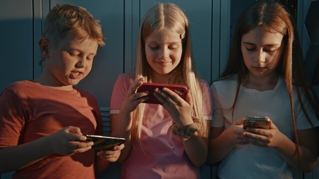Classmates Focused on Mobile Devices. Modern Back to School Experience. Concepts Related to Internet Safety, Cyberbullying Awareness, Educational Technology, Everyday School Life of Generation Alpha.