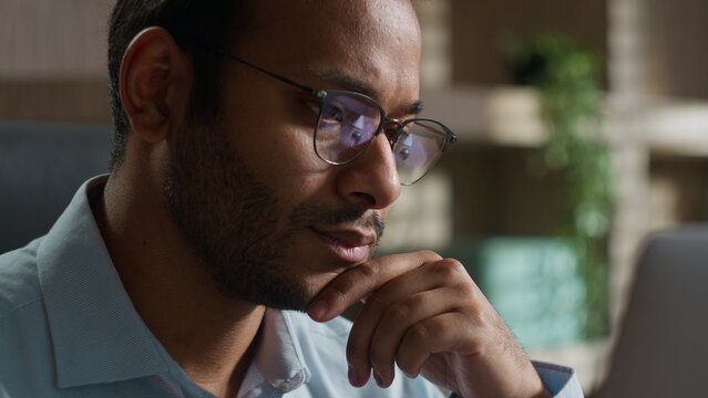 Pensive Indian American male business man reading bad news laptop indoors office thoughtful worker businessman thinking concerned problem computer solution worry anxiety difficulties failure bankrupt