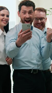 Multiracial business team celebrating good news mobile phone win in office happy colleagues excited businessmen businesswomen reading smartphone success corporate victory offer online deal celebration