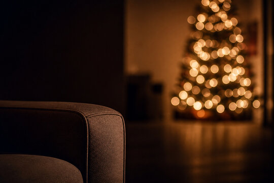 A dim living room at night lit only by the soft glow of a decorated