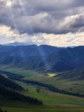 A ray of Sun falls through the clouds onto a farm in the mountains. Valley of Akkol river in Altai mountains.