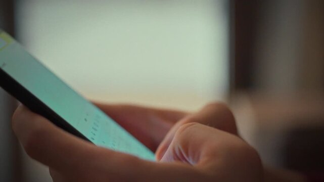 Man types rapidly on his smartphone, his fingers dancing across responsive touchscreen. This digital note-taking showcases how modern devices replace paper and pen for quick, efficient communication