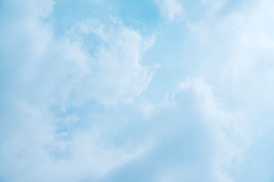 Serene light blue sky with soft, wispy white clouds, creating a peaceful and airy background. Sky or natural background
