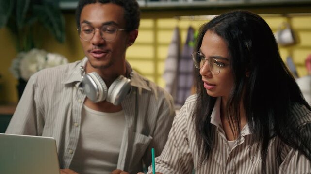 Multiethnic Arabian man and woman studying together at home using laptop students writing homework online class exam distant course education business freelancers teamwork teens learning pc at kitchen
