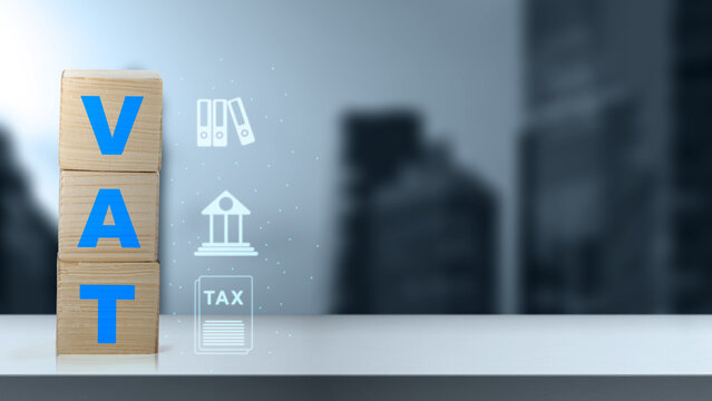 Wooden blocks spelling VAT stacked on a table with business icons against a blurred city background, representing value-added tax concept. Concept of house and property tax