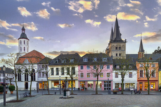 Historic houses on main square with Xanten Cathedral behind, Germany. Sunset sky with warm evening light