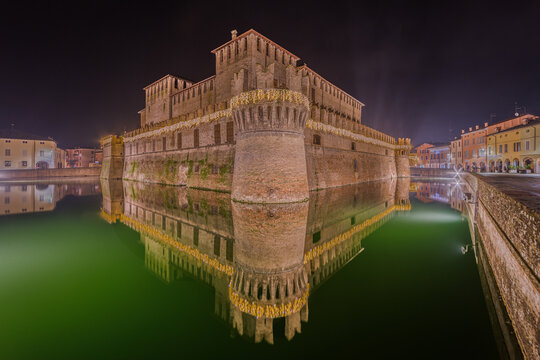 View of the illuminated Fontanellato Castle reflecting in the moat at night in Fontanellato, Emilia-Romagna, Italy.