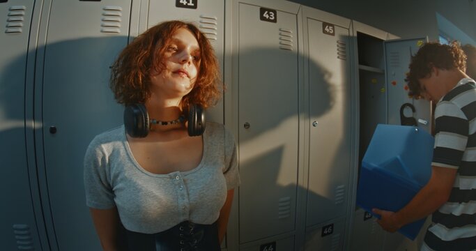 Portrait of Thoughtful Teenage Girl With Short Curly Hair Standing Near School Lockers. Introspective Mood, Solitude, Daydreaming and Authentic Adolescent Experience in a Busy High School Hallway.