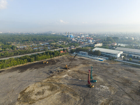 Aerial view of the Waste to Energy Facility Construction Project with heavy machinery on a cleared site near urban infrastructure, Kecamatan Denpasar Selatan, Bali, Indonesia.
