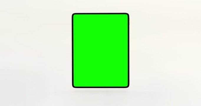 Green screen mockup of blank tablet computer falling and bouncing smoothly on white background
