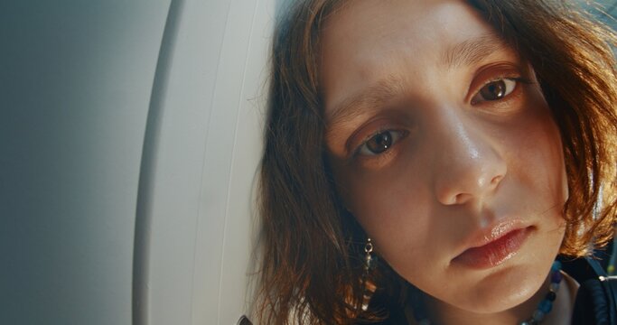 Moody Close Up Portrait of Thoughtful Teenage Girl With Slightly Tilted Head and Piercing, Looking Camera With Melancholic Expression. Emotional Depth, Vulnerability, Introspection and Coming of Age.