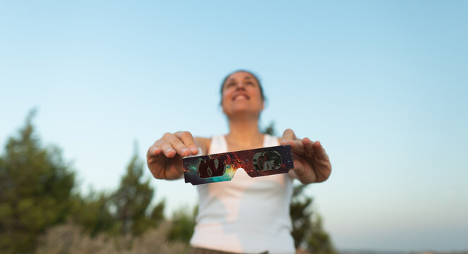 Woman holding solar eclipse glasses for safe viewing