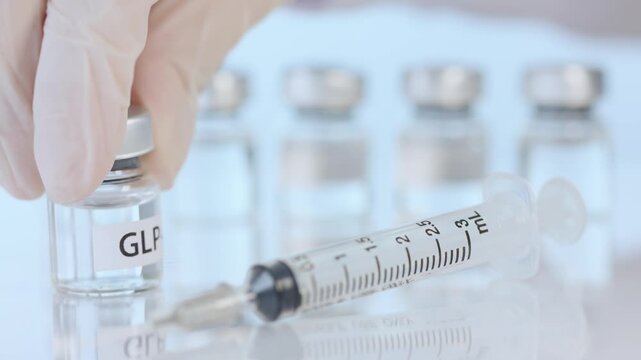 Professional hand wearing protective glove holding medical vial near syringe for hopeful weight management injection therapy clinic dose