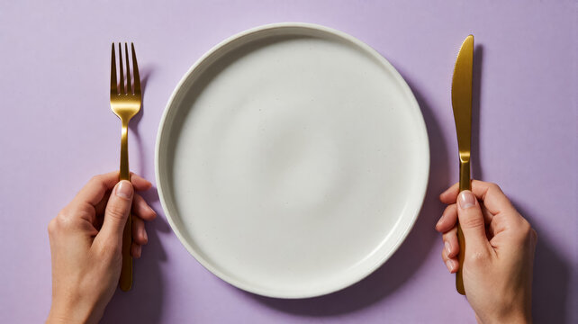 Minimalist table setting with empty plate and golden fork and knife