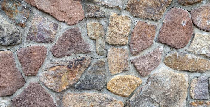 Natural Stone Wall Texture, A close-up view of a rustic stone wall showcasing irregular shapes and earthy tones in its construction