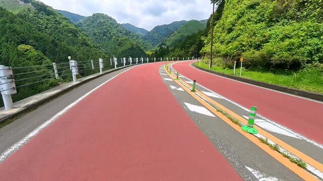 Motorcycle POV riding a mountain road past chevron warning signs
