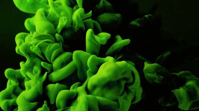 Vivid neon green ink clouds swirling slowly through dark water creating mesmerizing abstract shapes and fluid motion patterns in this professional high quality liquid footage for artistic visual backg