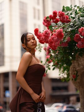Asian Woman Posing Near Blooming Pink Roses Outdoors