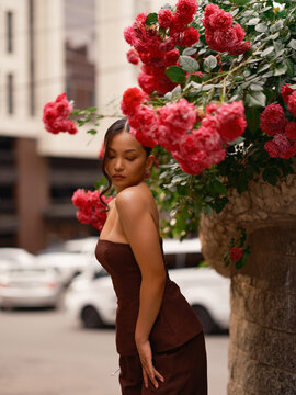 Asian Woman Standing Near Blooming Pink Roses Outdoors