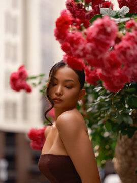 Asian Woman Standing Near Blooming Pink Roses Outdoors