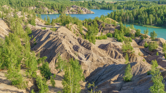 Scenic view of a tranquil lake surrounded by lush green trees and clay hills under a clear blue sky in a natural landscape setting in Kanduki, Tula region, Russia.