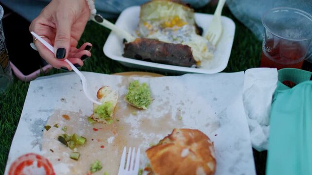 A young woman eats pide at a cozy street food festival, sampling various street foods. Close-up of the food. Summer vibes.