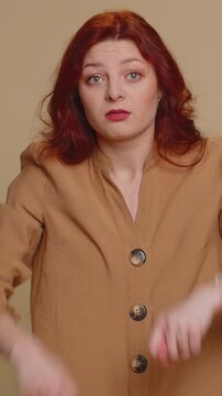 Angry aggressive redhead woman showing fig negative gesture, you dont get it anyway. Rapacious, avaricious, acquisitive. Body language. Refusal fig sign. Greedy avaricious girl on beige background