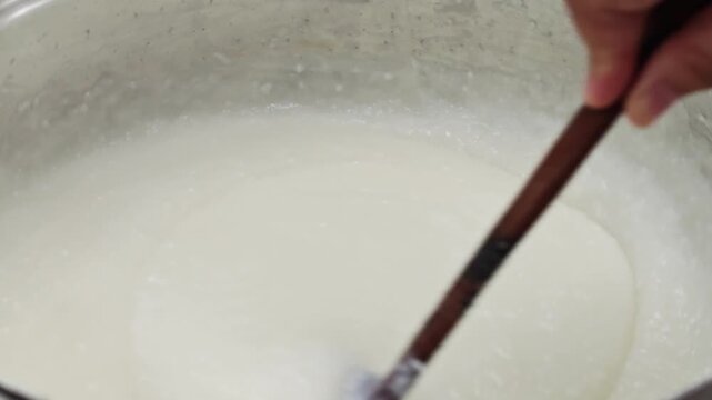 Macro cooking white congee with wooden spoon.