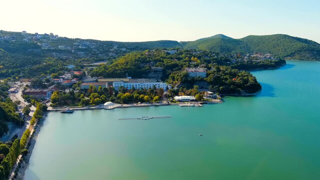 Abrau-Diurso, Krasnodar Krai, Russia. Lake Abrau. Embankment and village. Summer. The text on the embankment translates as the name of the village - Abrau-Diurso. Drone footage