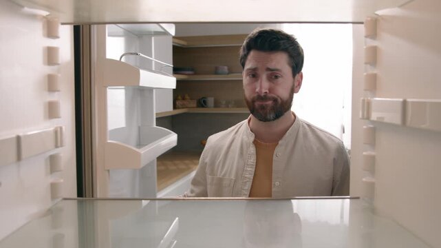 POV inside empty refrigerator hungry Caucasian man looking for food in kitchen sad upset male bachelor guy hunger no products crisis problem grocery shopping supermarket food delivery service at home