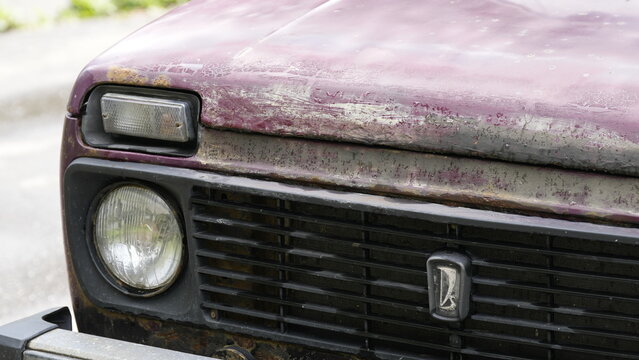 Front view of an old Lada Niva off road vehicle with weathered paint, rust details and authentic vintage appearance