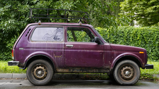 Old Lada Niva parked outdoors surrounded by greenery showing vintage design and signs of long term use