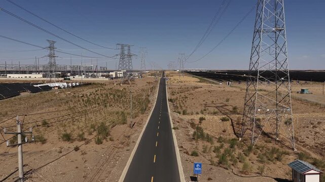 High-voltage Power Transmission Towers and Solar Farm Along Asphalt Road in Gobi Desert, Northwest China