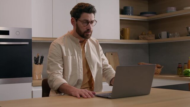 Caucasian business man talking online laptop video call at home kitchen remote male businessman teacher in glasses waving hi computer greeting students conference meeting negotiating work indoors