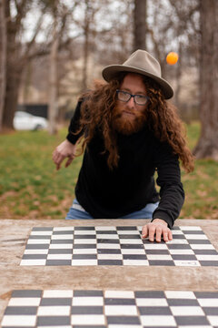 Hippie Man Drawing On Checkered Surface While Meditating Outdoors